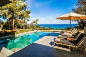 瓦西里科斯Luxury Villa Mon I Vassilikos的一个带2把躺椅和遮阳伞的游泳池