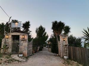 沃丽曼村Vigla Villas的车道上的一个门,有栅栏和棕榈树