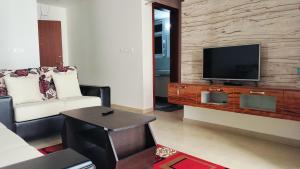 班加罗尔SOLACE Premium 2BHK Apartment near Manyata Tech Park And Hebbal的一间带电视和沙发的客厅