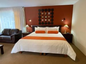 乔卢拉Capital O La Huerta Golf & Hotel的一间卧室配有一张大床和一把椅子