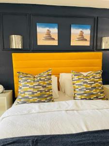 肯普顿帕克Aneiwa airport lodge的一间卧室配有一张带黄色床头板和枕头的床。