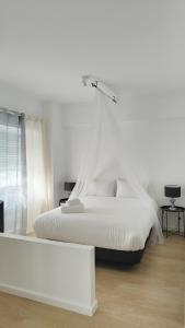 沙尔内卡Villa Paraíso da Caparica的白色的卧室设有白色的床和窗户。