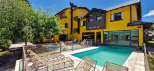圣卡洛斯-德巴里洛切康普雷由巴谢41号公寓的一座黄色建筑前的游泳池,配有椅子
