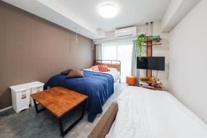 东京Seaside Tamachi - Vacation STAY 15584的一间卧室配有两张床、一张桌子和一台电视。