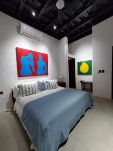 El TamarindoCASA ROMA Hotel Boutique的一间卧室配有一张大床,墙上有两幅画作