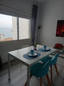 锡切斯Loft espectacular vista al mar的一张带两把蓝色椅子的餐桌和窗户
