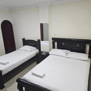 巴兰基亚Hotel Barranquilla Inn的配有白色床单的客房内的两张床