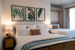 圣何塞德尔卡沃Flamboyan Hotel & Residences的卧室内的两张床,墙上有三幅画
