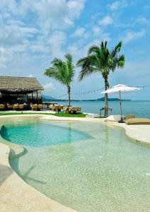 苏梅岛Le Shelby Samui Beach Resort Cottage的毗邻大海的棕榈树游泳池