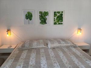 索罗卡巴Sobrado charmoso em localização central!的卧室配有一张带两张桌子的床,墙上有两张照片