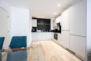 南安普敦Luxury Apartment by Ocean Village Marina的厨房配有白色橱柜和玻璃桌