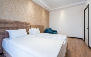 第比利斯Olympus Hotel By Umbrella的卧室配有一张白色大床和一张蓝色椅子