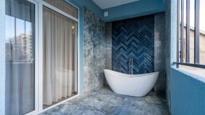 第比利斯Olympus Hotel By Umbrella的带浴缸的浴室和窗户