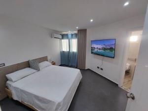 El YaqueYaque Suite的卧室配有一张床,墙上配有电视。