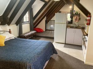 但尼丁Arden Country House - The Chalet Bed and Breakfast的一间卧室配有一张床,厨房配有冰箱