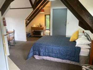 但尼丁Arden Country House - The Chalet Bed and Breakfast的阁楼卧室配有蓝色床