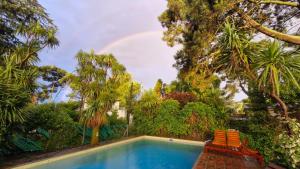 马德普拉塔Casa con piscina en Sierra de los Padres的一个带两把椅子和彩虹的游泳池