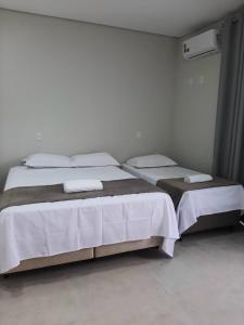 圣若昂-巴蒂斯塔-杜格罗里亚Pousada Lobo Guará的一间卧室配有两张带白色床单和枕头的床。