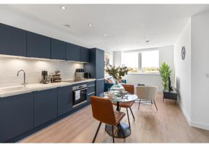 贝肯翰姆Beckenham Beauty: Modern 1-Bedroom Abode的厨房配有蓝色橱柜和桌椅