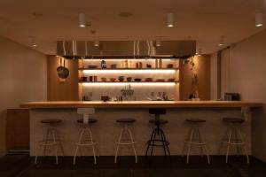 东京CAFE/MINIMAL HOTEL OUR OUR的厨房设有酒吧,四周摆放着凳子