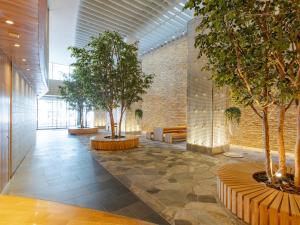 仙台The OneFive Sendai的建筑里带有树木和长凳的走廊