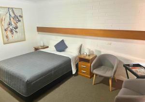 米尔迪拉欧罗娜汽车旅馆的一间卧室配有一张床、一把椅子和一张书桌