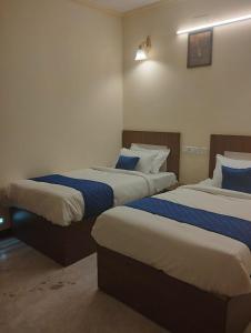 钦奈A.R Residency的一间卧室配有两张带蓝白色床单的床