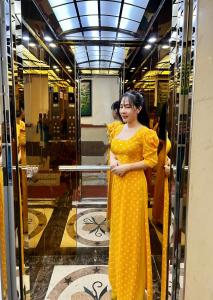 胡志明市Gia Hân Hotel的站在窗户上的穿着黄色衣服的女人