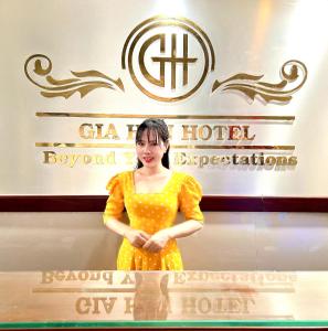 胡志明市Gia Hân Hotel的站在标志前身穿着黄色衣服的女人