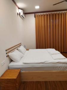 马米基里Oi Beach的一间卧室配有一张带白色床单的大床