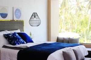 帕干岛The Willow Phangan的一间卧室配有一张带蓝色枕头的床和一扇窗户。