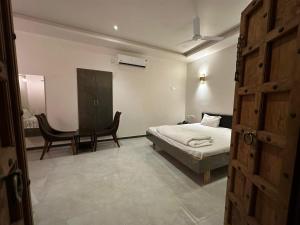 MundraHotel Surbhi的一间卧室配有一张床、一张桌子和一把椅子