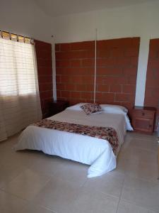 VillamaríaLA RIVERA HOSTERIA CAMPESTRE的一间卧室设有一张床和砖墙
