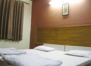 阿格拉Hotel Ajay International Agra的一间卧室配有两张带白色床单和木制床头板的床。