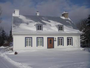 St-Pierre-de-l'Île-d'OrléansAu Vieux Foyer的白色的房子,上面有雪