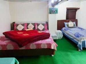 乔斯希马特YATRA HOMESTAY Joshimath的一间卧室配有两张带红毯的床