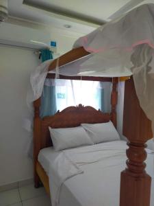 GaluTHE ROYAL STAYS的卧室配有带白色床单的木制天蓬床