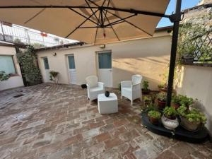 基亚拉瓦莱Affittacamere Il Cortile的庭院配有白色的椅子和遮阳伞。
