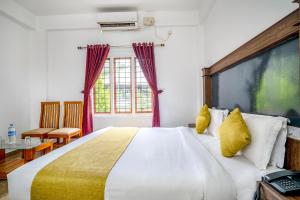 蒙纳FabHotel Abrigo Residency的卧室配有一张带黄色枕头的大型白色床。