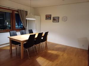 基律纳Kiruna accommodation Läraregatan 19 b的一张带黑色椅子的餐桌和墙上的时钟