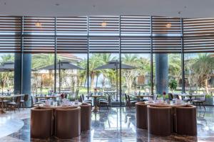 岘港KOI Resort & Residence Da Nang的餐厅设有桌椅和大窗户。