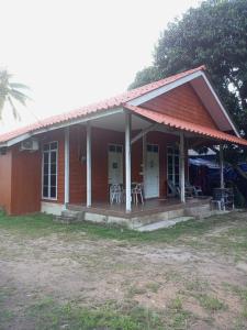 瓜拉丁加奴Bilik Bajet RM70-RM90的一座红色的小房子,设有门廊和椅子