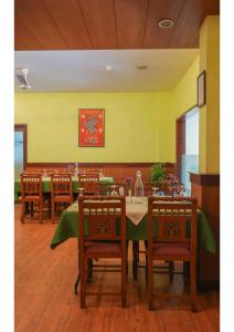 KāladiHotel Aramana的用餐室配有桌椅和黄色墙壁
