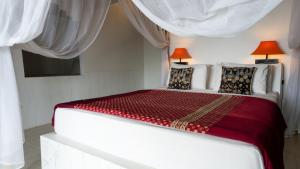 艾湄湾Anda Amed Villas & Spa的白色卧室配有一张带红色床单的大床