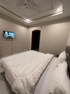 伊斯兰堡Sunrise Residence的卧室配有白色的床,墙上配有电视