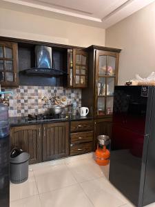 伊斯兰堡Sunrise Residence的厨房配有木制橱柜和黑色冰箱。