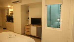 贝克西Apartemen Grand Kamala Lagoon by Cheapinn的一间卧室设有一张床、一台电视和一个窗口。