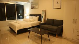 贝克西Apartemen Grand Kamala Lagoon by Cheapinn的一间卧室配有一张床、一张沙发和一把椅子