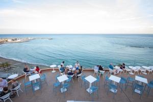 贝纳尔马德纳Hotel Benalmadena Beach的一群人坐在甲板上的桌子上,俯瞰大海