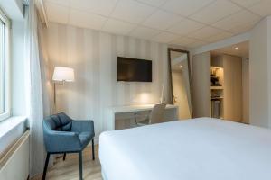费尔德霍芬康宁小夫NH埃因霍温会议中心酒店的酒店客房配有一张床、一把椅子和一台电视。